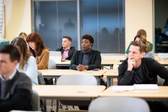 Business students sit in class and listen to their professor